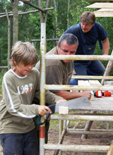 Zwei Männer und ein Junge bauen gemeinsam ein Klettergerüst für einen Spielplatz © Foto: Elke Mocker (LASA)