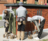 Junge Männer verschönern mit Graffiti im Auftrag der Stadt eine Strom-Versorgungsstation im Wohngebiet.