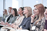 Mehrere Frauen sitzen nebeneinander gereiht in einer Veranstaltung und blicken nachdenklich nach vorne (Quelle: AdobeStock: yurolaitsalbert)