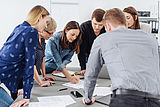 Sechs Mitarbeitende beugen sich über einen Bürotisch und zeigen mit einem Stift auf ein Schriftstück © Foto: AdobeStock: contrastwerkstatt