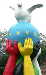 Stele: Viele Hände verschiedener  hautfarben halten die Weltkugel auf der eine Friedenstaube sitzt © Foto: Sylvia Krell