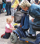 Kleinkind untersucht Rollstuhl einer gehbehinderten älteren Frau © Foto: Sylvia Krell (LASA)